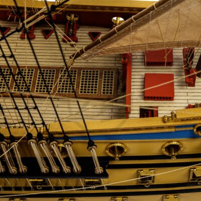 Ponts détaillés de la maquette de L’Ambitieux avec embarcations, canons et décorations fidèles au XVIIe siècle.
